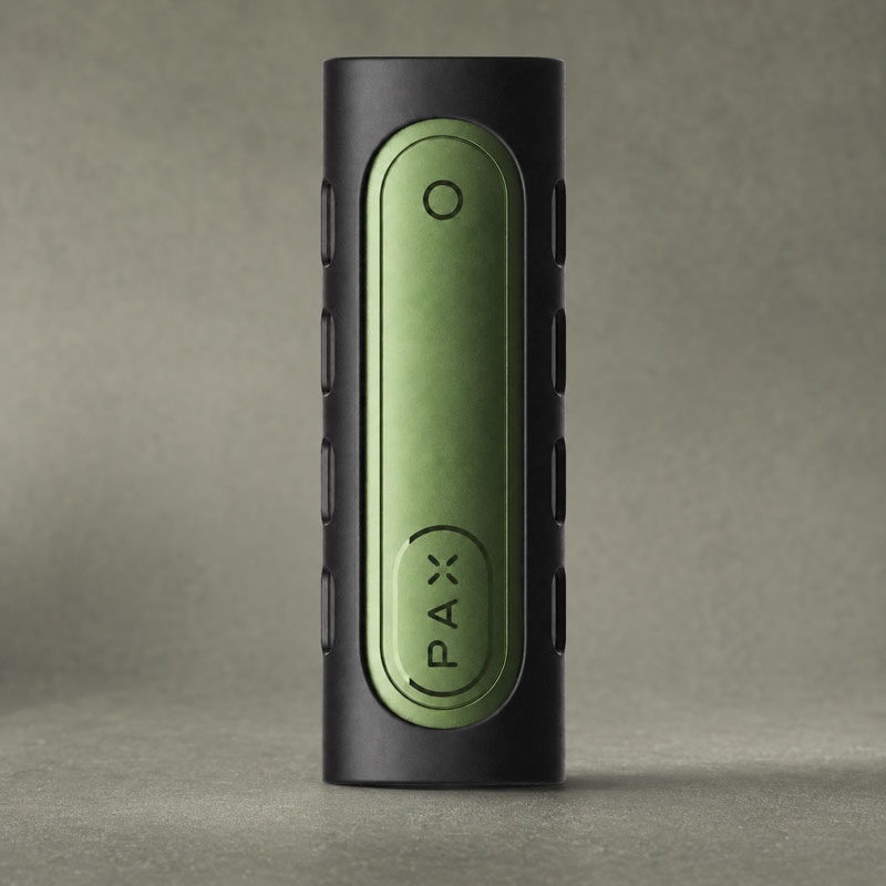 PAX Flow Grip Sleeve in black and green on a textured grey-green studio background.