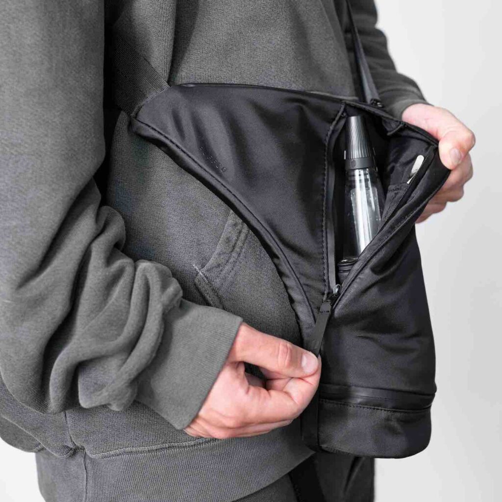 Person carrying Puffco Journey Bag against grey wall
