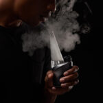 Person exhaling vapour while using Puffco Peak Pro