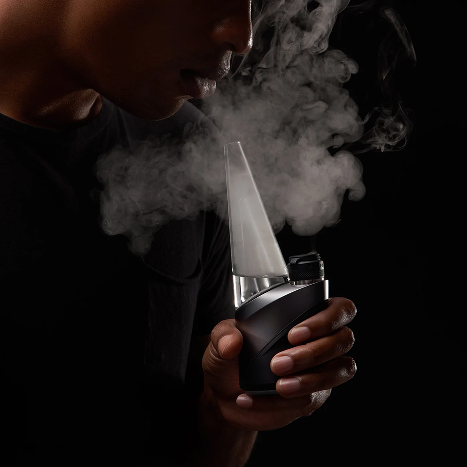 Person exhaling vapour while using Puffco Peak Pro
