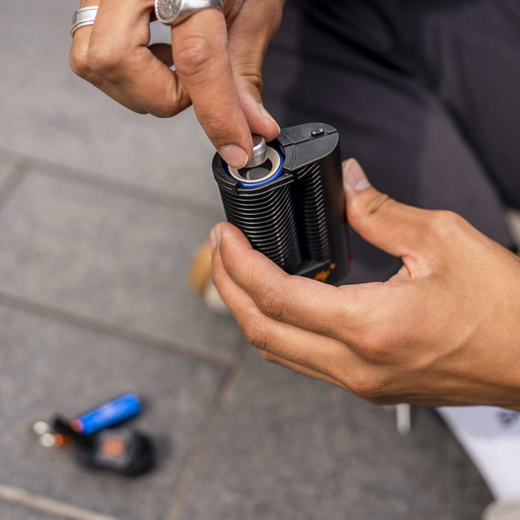 Crafty+ dry herb vape being loaded by hand outdoors
