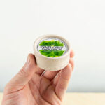 A mans hand holding the hemp grinder indoors.