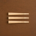 Top-down view of three king size pre-rolled cones arranged neatly on a wooden table background.