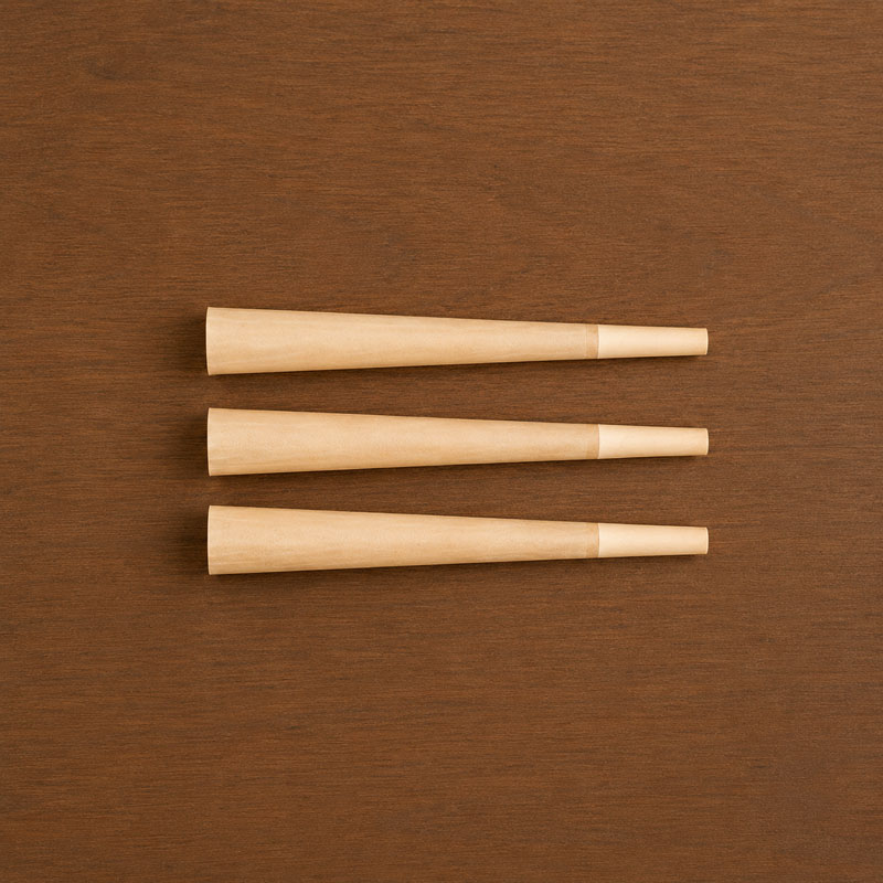 Top-down view of three king size pre-rolled cones arranged neatly on a wooden table background.