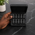 Hand holding the Prefill Set with multiple stainless steel dosing capsules in black storage case