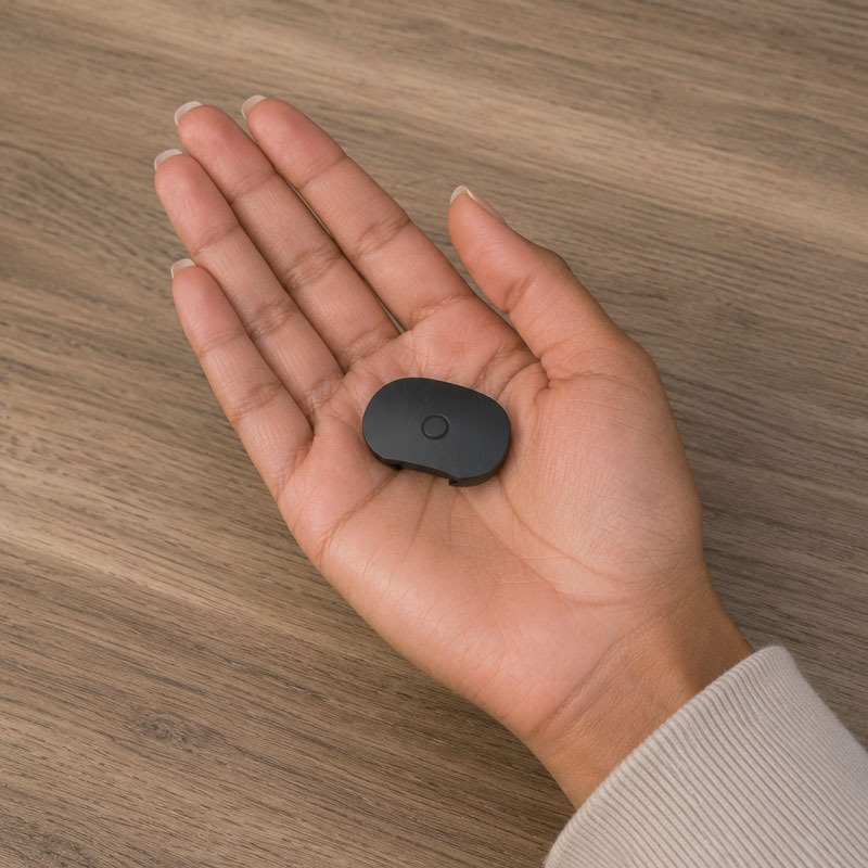 Flat black PAX 4 mouthpiece resting on an open hand above a wooden table