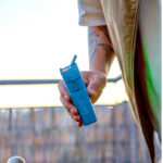 man holding blue vape outside