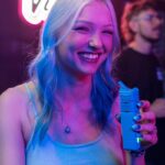 blonde woman laughing in a bar holding the veazy