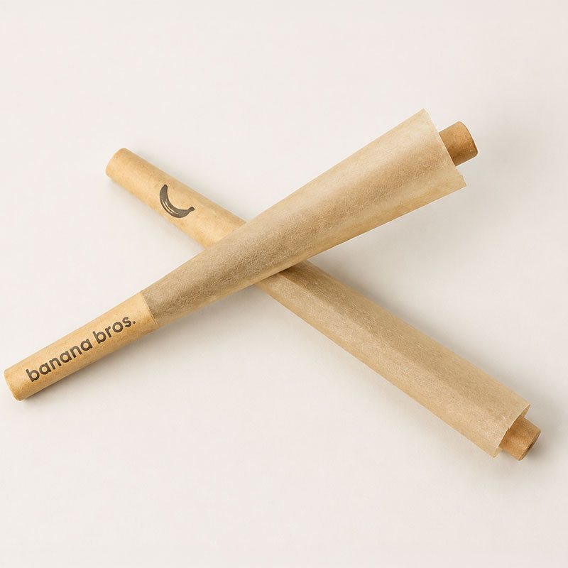 Five Banana Bros short pre-rolled cones with slight natural creases and paper variations arranged diagonally on a rustic wooden tabletop.