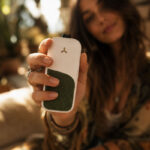 Woman holding a white AirVape Legacy CORE vaporizer in a close-up outdoor lifestyle setting
