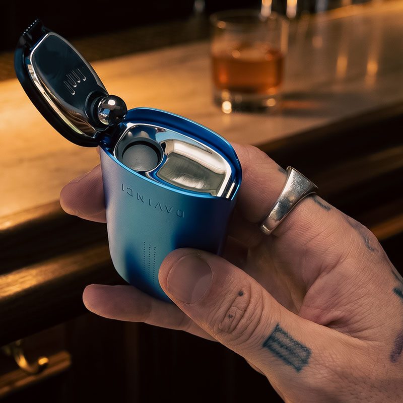Blue DaVinci IQ Core vaporizer held in a hand with the top lid open