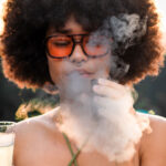 Woman using the Dr. Dabber Ghost 2 vaporizer with visible vapour