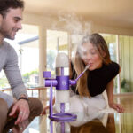 Woman using a purple Stündenglass Gravity Infuser indoors