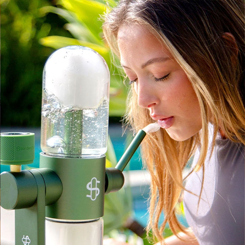 Woman using a green Stündenglass Gravity Infuser outdoors