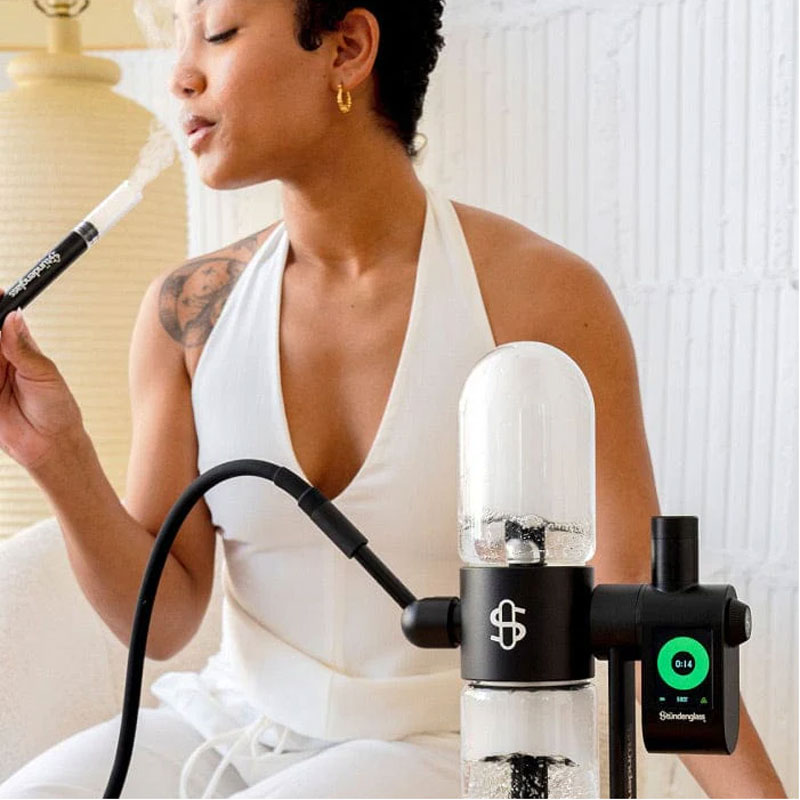 Woman using the black Stündenglass Gravity Infuser with a hose indoors