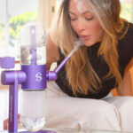Woman using the purple Stündenglass Gravity Infuser indoors