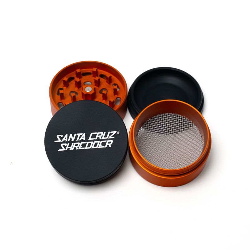 Santa Cruz Shredder Split Series orange and black grinder opened to show the teeth, screen and collection chamber