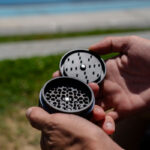 G Pen 3-Piece Slim Grinder held open outdoors showing the grinding chamber and lid
