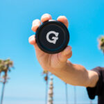 G Pen 3-Piece Slim Grinder held in hand outdoors showing the G logo lid