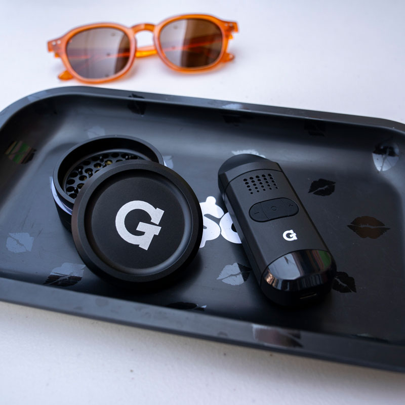 G Pen 3-Piece Slim Grinder on a tray beside a G Pen device and sunglasses