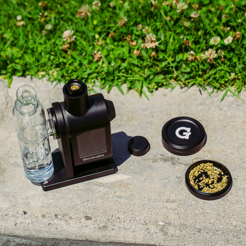 G Pen 3-Piece Slim Grinder beside a vaporizer setup with ground dry herb in the collection chamber